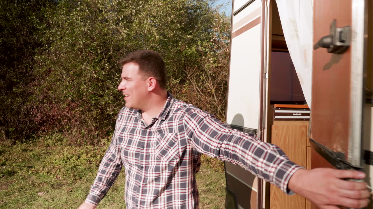 미소 짓는 부부가 레트로 캠퍼 밴에서 나온다