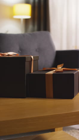 vertical video of presents in gift wrapped boxes decorated with ribbon on table in lounge