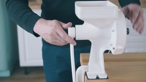 man-installs-and-tests-handle-to-flour-grinder-in-kitchen