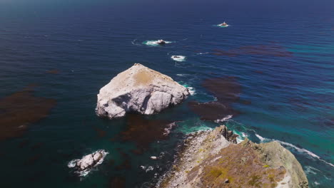 bare rocks of different size peeping out from deep blue water. pacific ocean at the coastline of california, usa from top.