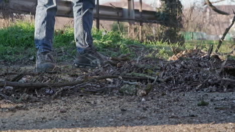 person using plastic rake to throw away leaves and pieces of wood from the ground - slow motion