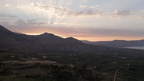 Aerial-Pedestal-of-Landscape-and-Mountains-in-Crete,-Greece-at-Sunset-with-Sun-Flares-and-Warm-Colours