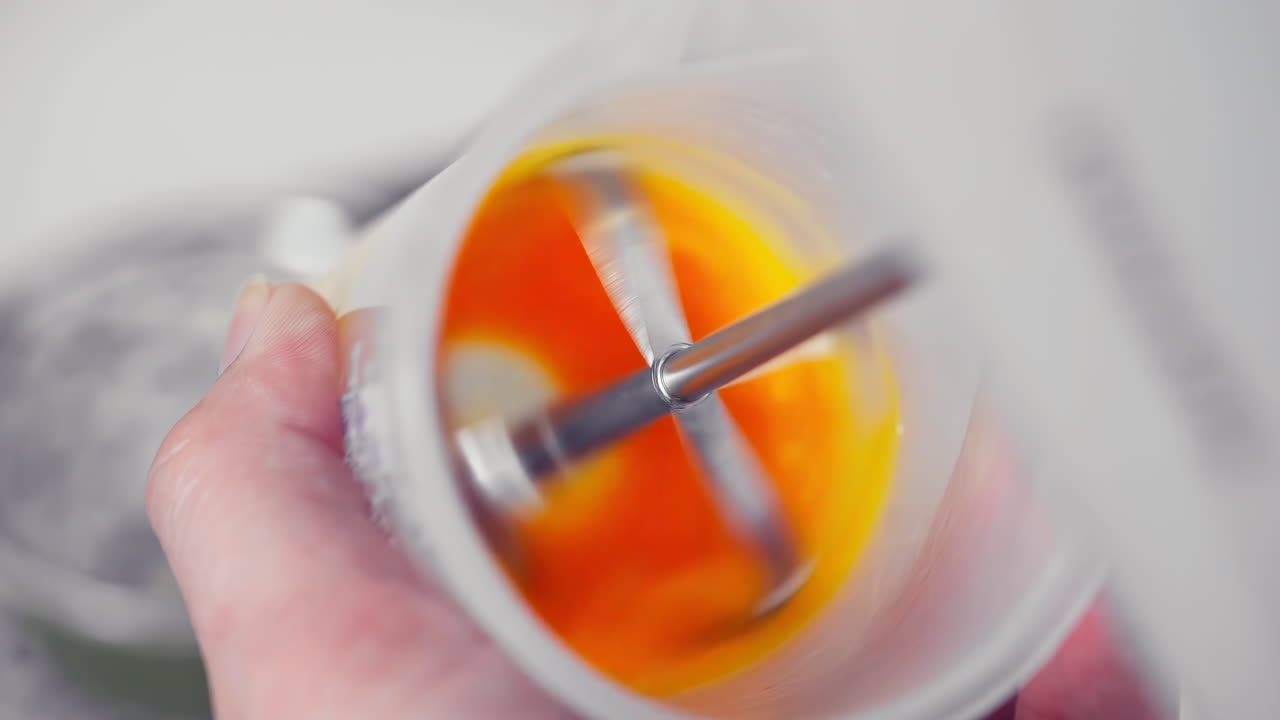 믹서 털로 플라스틱 컵 안에 요리사 손 구타 계란을 닫습니다