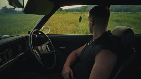 man driving through countryside in vintage car
