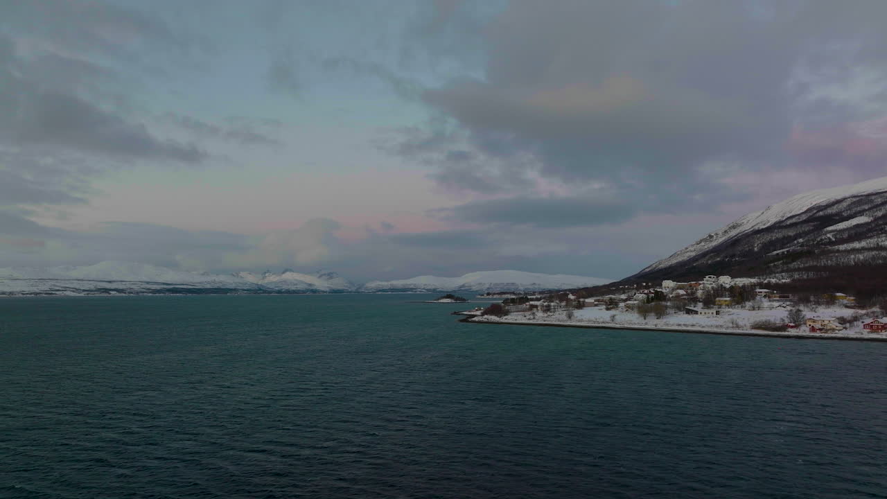 눈 덮인 산맥으로 물 위로 낮게 날아가는 드론 샷