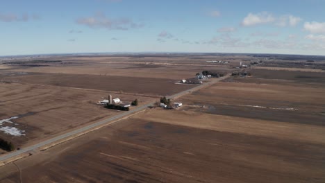 Rural-farm-with-barn-and-silo-standing-out-in-brown-fields-before-planting-in-off-season