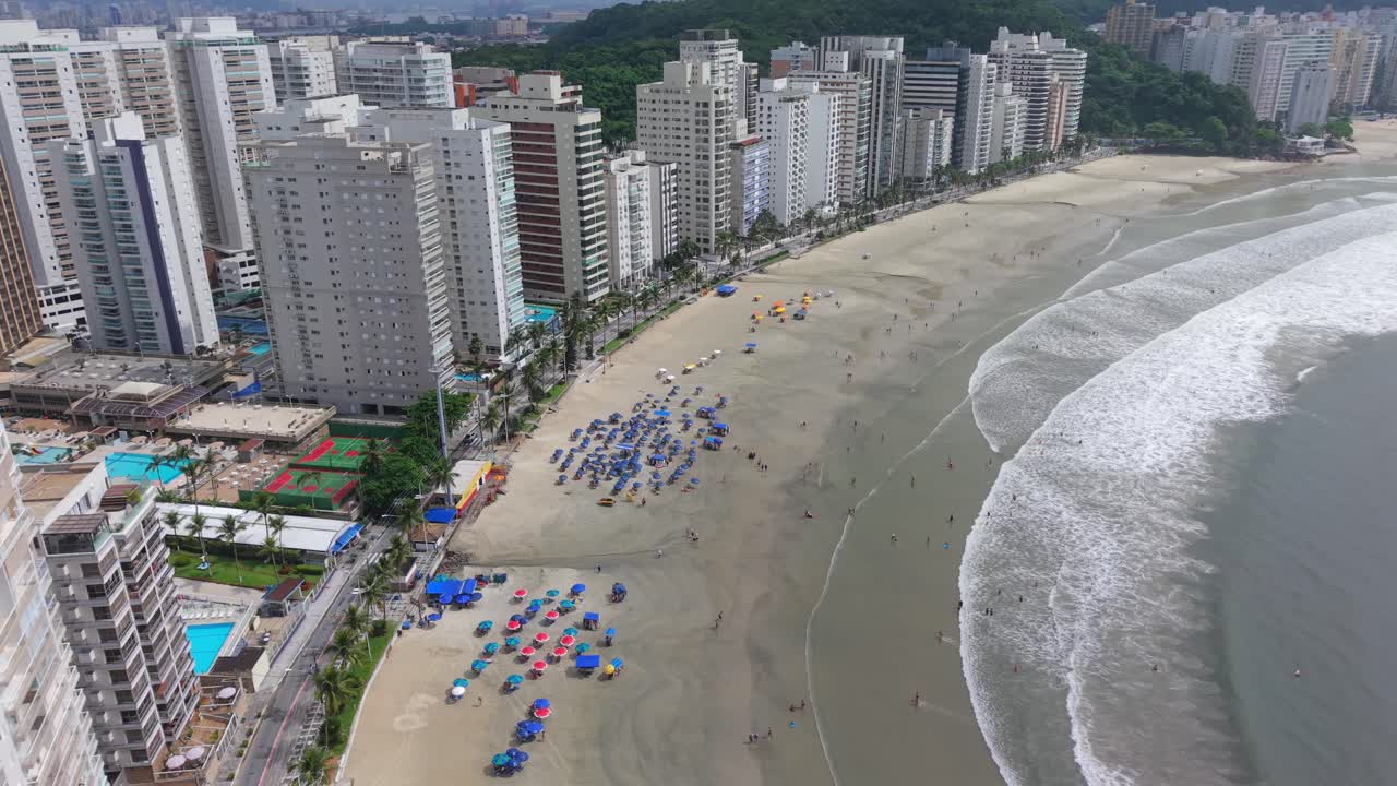 Praia das Asturias Guarujássa, São Paulossa, Brasiliassa, Avenida General Monteiro de Barrosin varrella, hiekkaranta, aurinkovarjot, Atlantin valtameren aallot ja asuinkerrostalot, ilmakuva, hidas liuku.