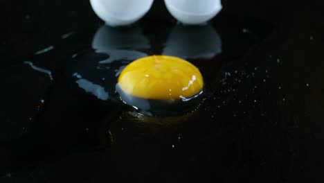 tilt down to reveal and perfectly cracked egg with the raw yoke and egg whites spilled out in front of it