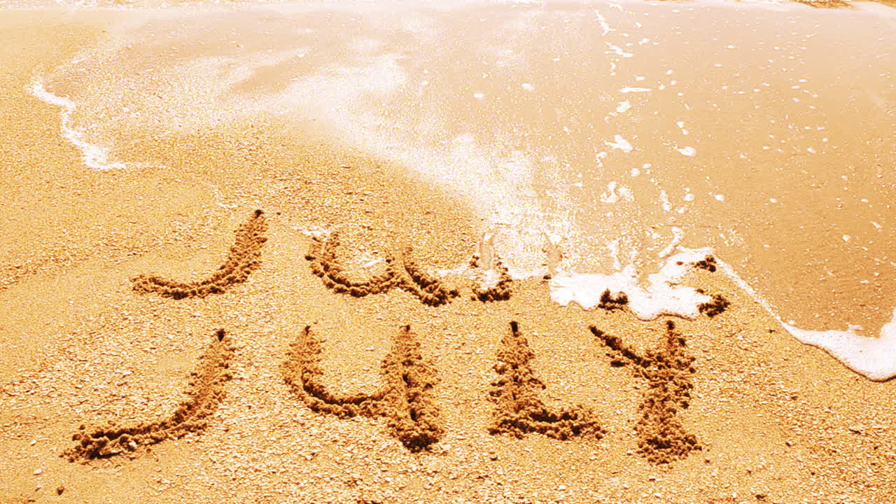 Iscrizione del nome del mese sulla sabbia, la spiaggia. Scatto sulla spiaggia.