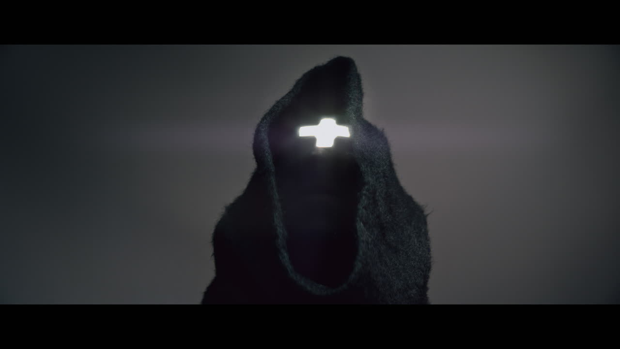 Masked man with cross of light glowing on his face moves his head up