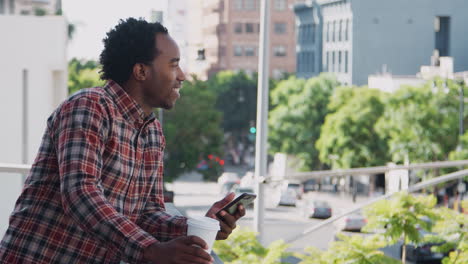 Businessman-Standing-Outside-Office-Building-Using-Mobile-Phone-With-City-Skyline-In-Background