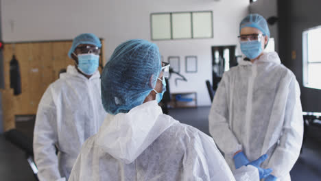 team of health workers wearing protective clothes discussing together in the gym