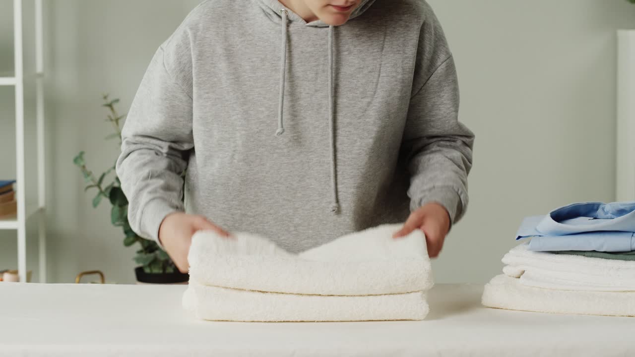Young Woman Folding and Stacking Clean Laundry