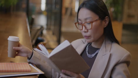 woman reading and drinking coffee in a cafe