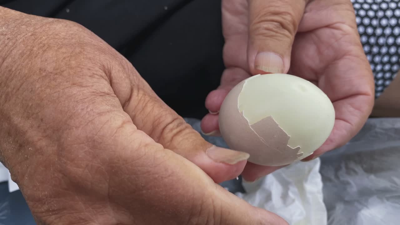 Peeling an egg. Close up of elderly hands