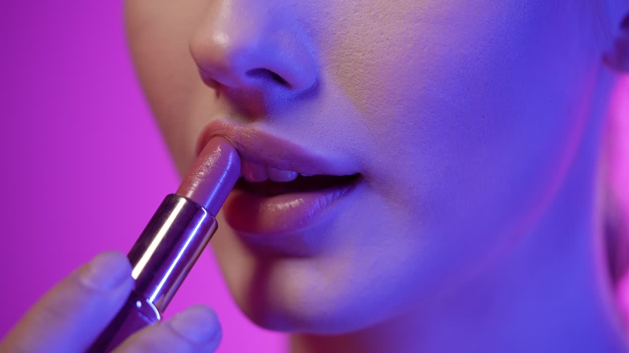 una foto de cerca de los labios de una hermosa joven mientras presiona sus labios para extender su lápiz labial recién aplicado después de prepararse para la noche del club uniformemente en cámara lenta