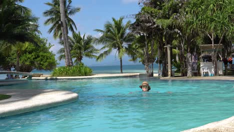 dos palmas island resort, puerto princesa, palawan, filipinas - encantadora turista nadando en una hermosa piscina infinita rodeada de palmeras en un día soleado - toma de bajo nivel