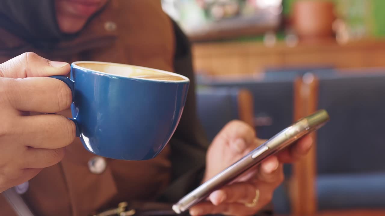 카페에서 커피를 마시며 스마트폰을 사용하는 여자