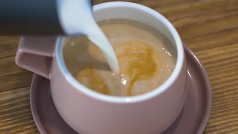 Pouring-frothed-milk-into-coffee-shot,-cappuccino-making-closeup