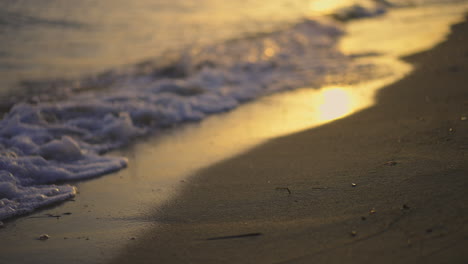 waves gently rolling onto a sandy beach at sunset