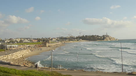 wide shot, mediterranean coastal city, beach and boardwalk, sunny beautiful day