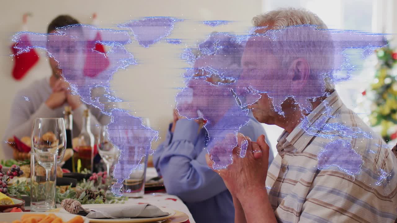 Map appearing sparking senior man, family clasping hands for holiday prayer, faint overlay fading