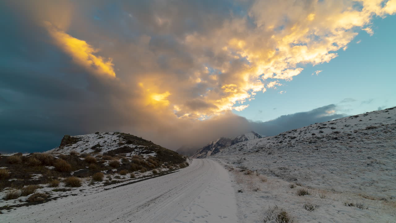 lapso de tiempo de nubes iluminadas por el sol rodando sobre la carretera cubierta de nieve en torres del dolor