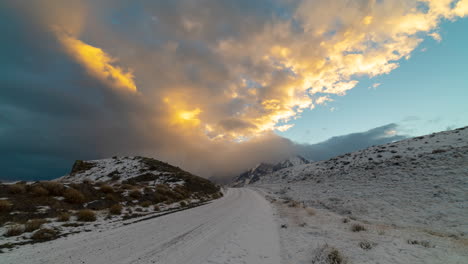 time lapse of sun lit clouds rolling over snow covered road at torres del paine