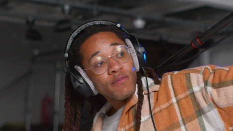 close up of male film sound recordist wearing headphones holding microphone boom pole shooting movie or video in studio 2