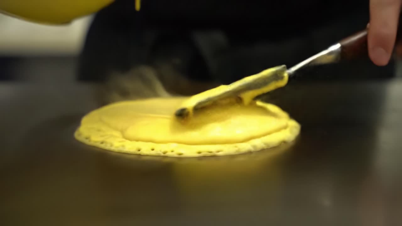 Watch as the art of cooking comes alive in this mesmerizing video showcasing the delicate process of creating a perfectly crafted pancake from start to finish!