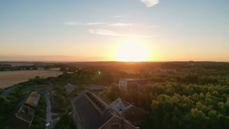 Drone-shoot-flying-backwards-showing-the-sunrise-over-an-abandoned-building-in-a-coal-mine-in-Kent-UK