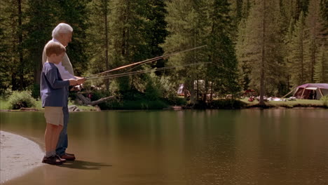 two generations fishing by a lakeside campsite