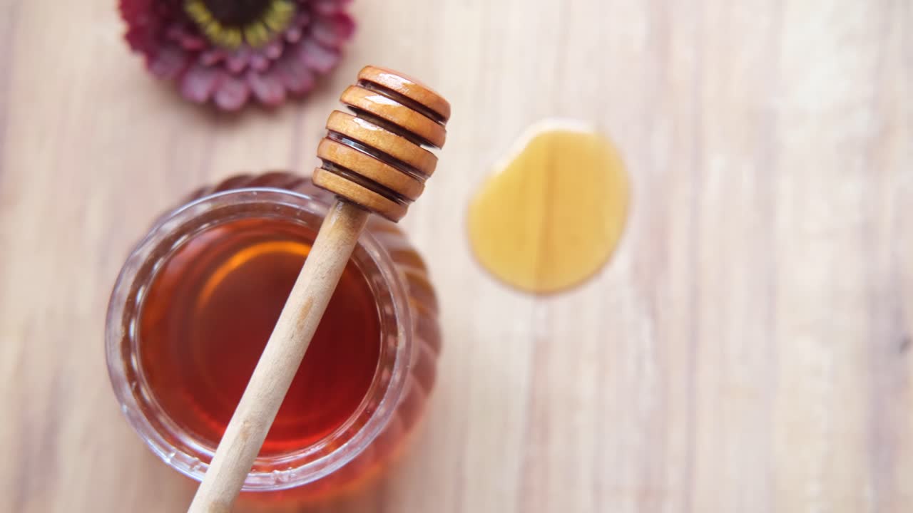Vasetto di miele con spargimiele e fiore