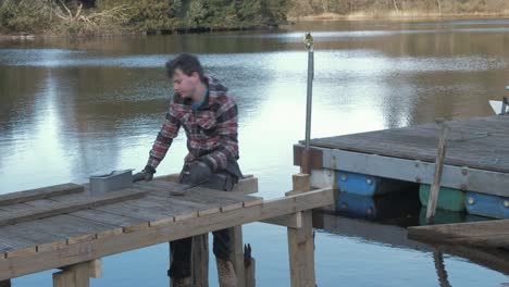 young male handyman building wooden jetty