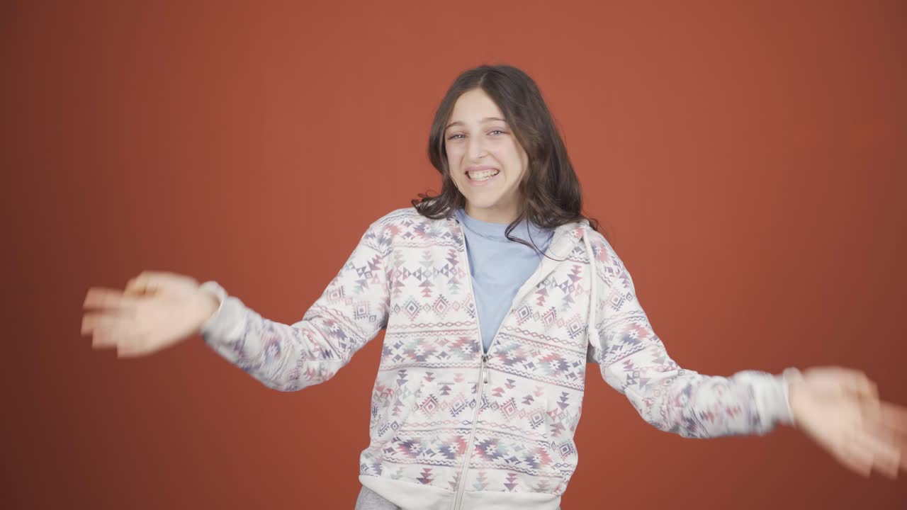 행복한 젊은 여성이 카메라를 향해 손을 흔들고 있습니다.