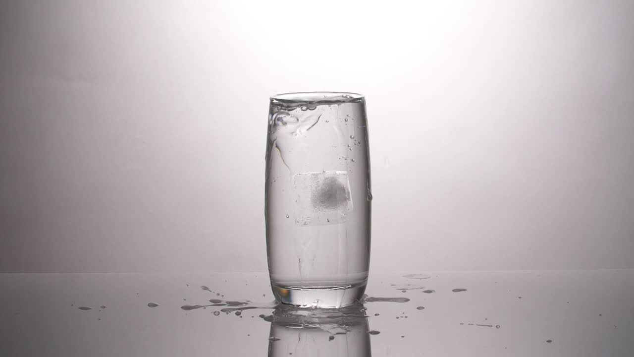 Ice cube dropped into a glass of water