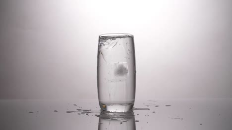 ice cube dropped into a glass of water