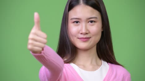 young beautiful asian woman giving thumbs up