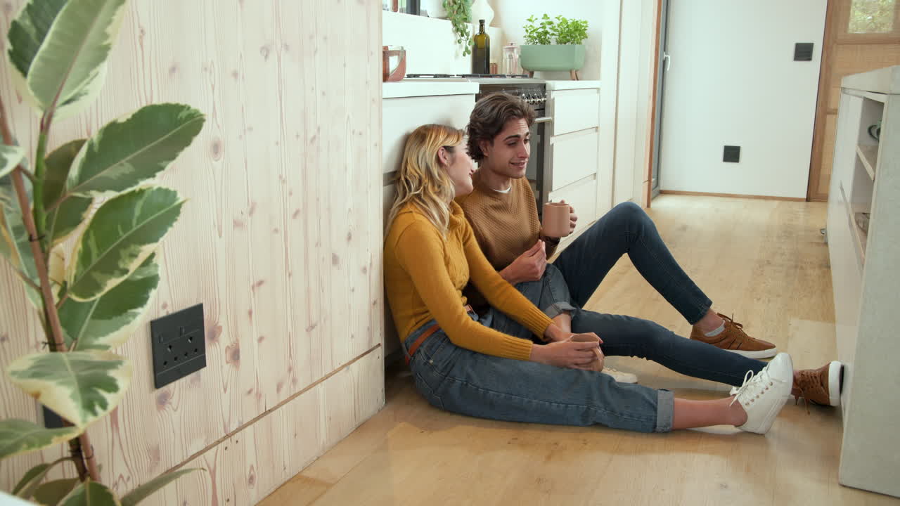 Couple relaxing at home, enjoying coffee and laughter in cozy kitchen