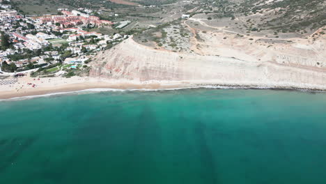 Panning-drone-shot-on-a-sunny-day-of-the-beach-and-town-at-Luz-Portugal