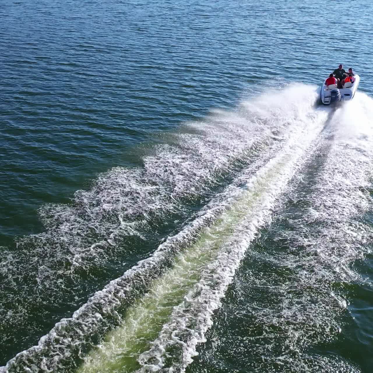 Motor boat rushes along the river. Beautiful view of white foam on blue river water behind the boat on nature background. Aerial view.