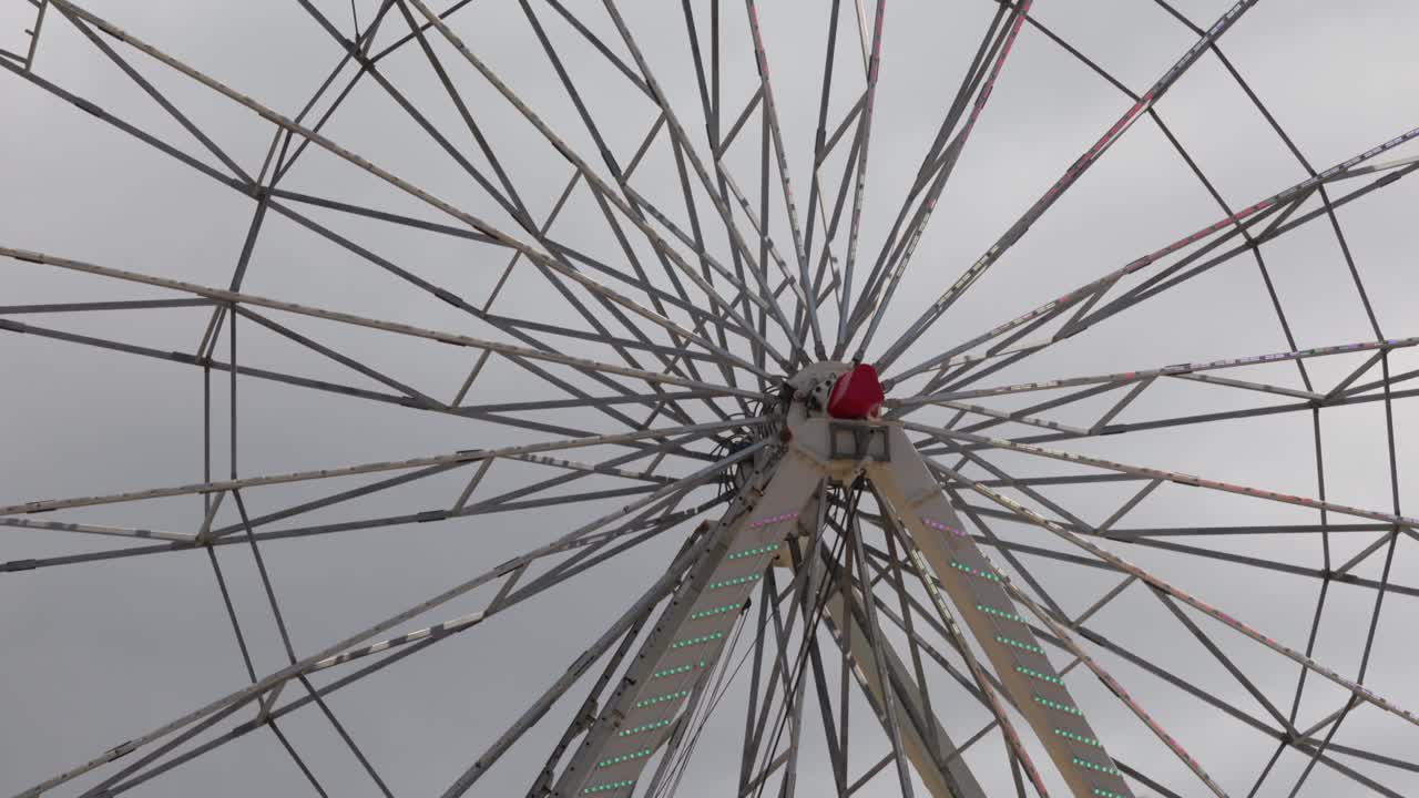 A detailed close-up shot of the central wheel and mechanism of a Ferris wheel in motion at a spring festival, highlighting the engineering and movement