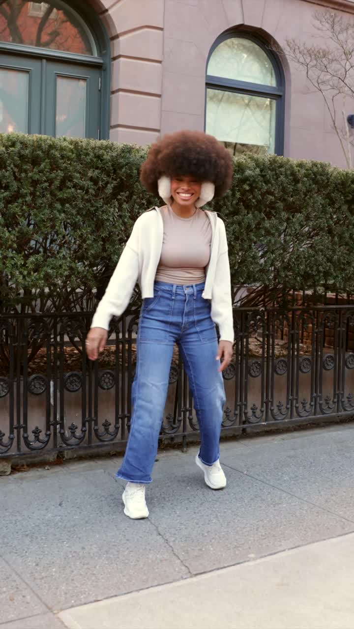 Donna alla moda con afro e paraorecchie, ritratto all'aperto