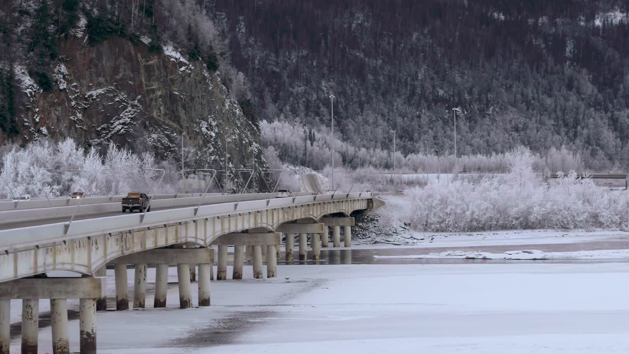 자동차는 알래스카 주 앵커리지에서 얼어붙은 강 위의 다리를 가로질러 이동합니다.
