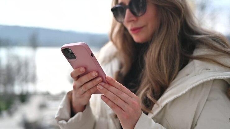 Donna che scorre il feed del telefono seduta su una panchina verde in un parco