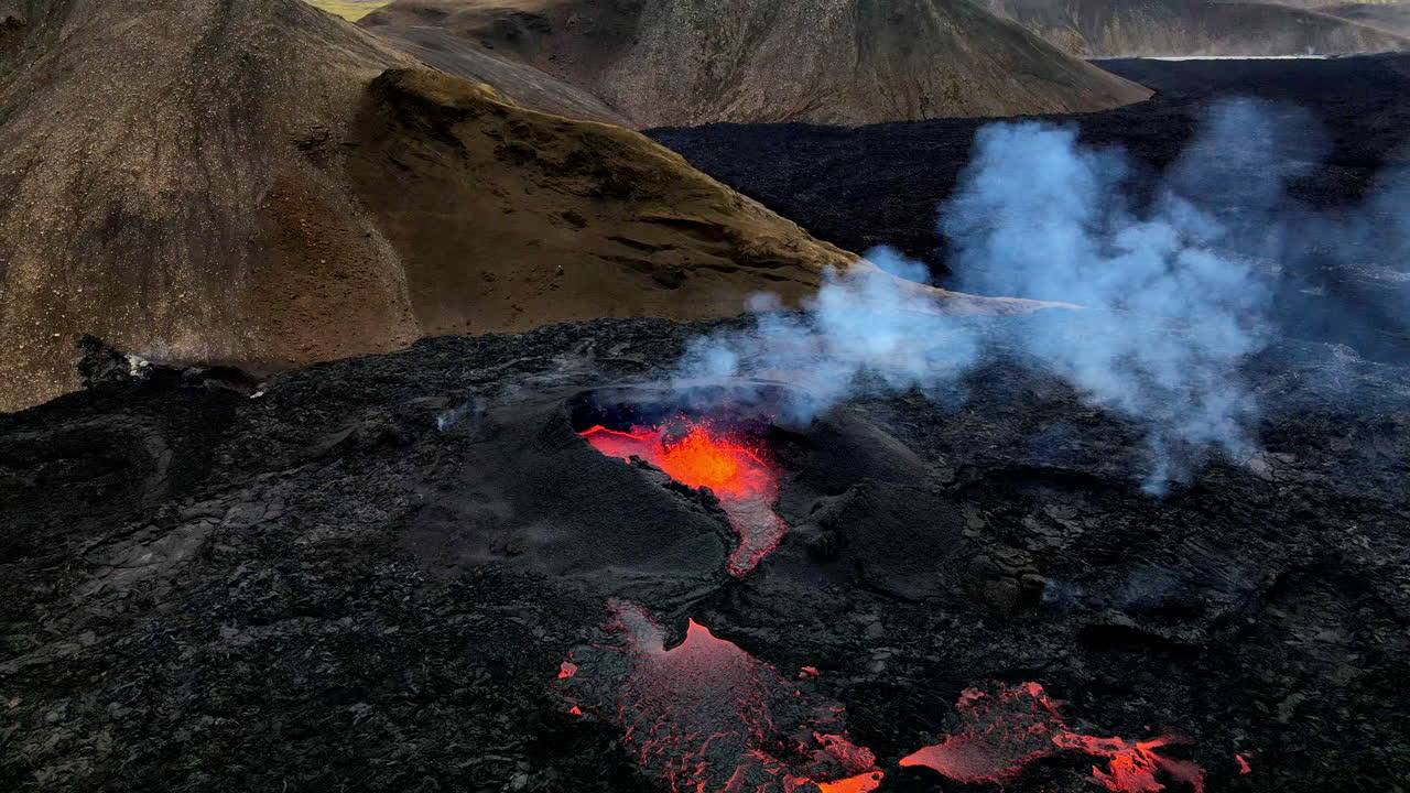Close circular aerial shot of the hot lava, magma and ashes coming out of mouth of the crater in Fagradalsfjall, Iceland