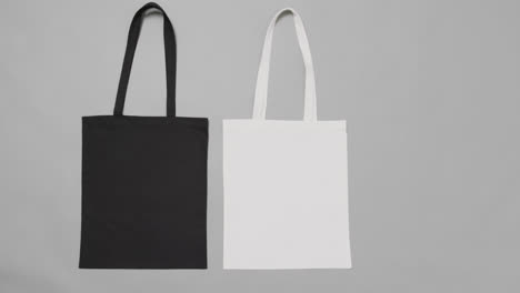 Close-up-of-white-and-black-bags-on-grey-background,-with-copy-space,-slow-motion