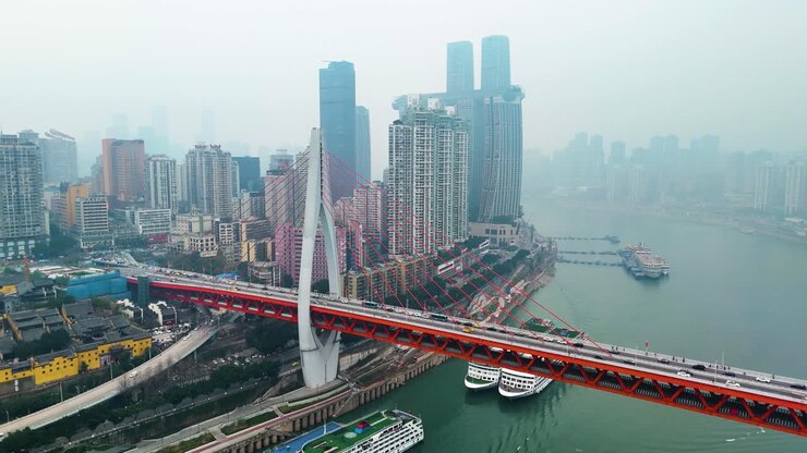 Aerial view of the stunning Chongqing cityscape during the day, featuring a modern bridge over the river with towering skyscrapers, showcasing the city's vibrant development and architectural design.