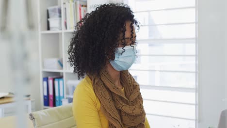 woman wearing face mask sitting on her desk at office