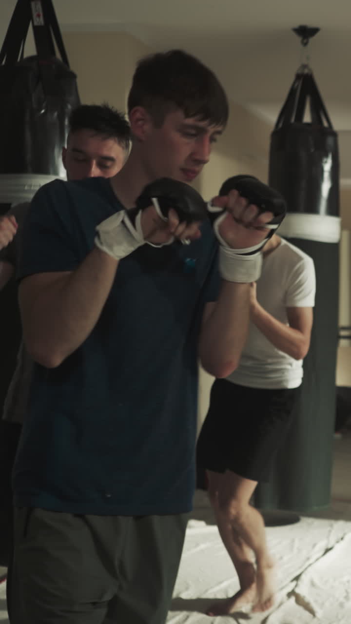 los boxeadores corren calentando las manos en el gimnasio de lucha. los kickboxers hacen ejercicios en grupo juntos en la pista de patinaje en el club de artes marciales en cámara lenta. el equipo de deportistas de combate